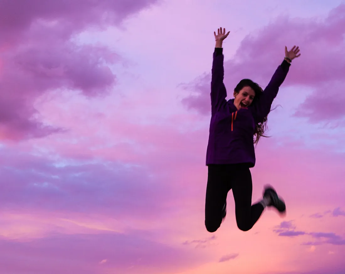 Catherine, Gründerin von EnergieFlow, heute: springend vor Freude vor rosa Himmel